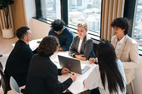 Eine Gruppe von Mitarbeitern sitzen bei einem Meeting und besprechen Vorgehensweisen zur Risikominimierung im Rahmen des Compliance Managements.