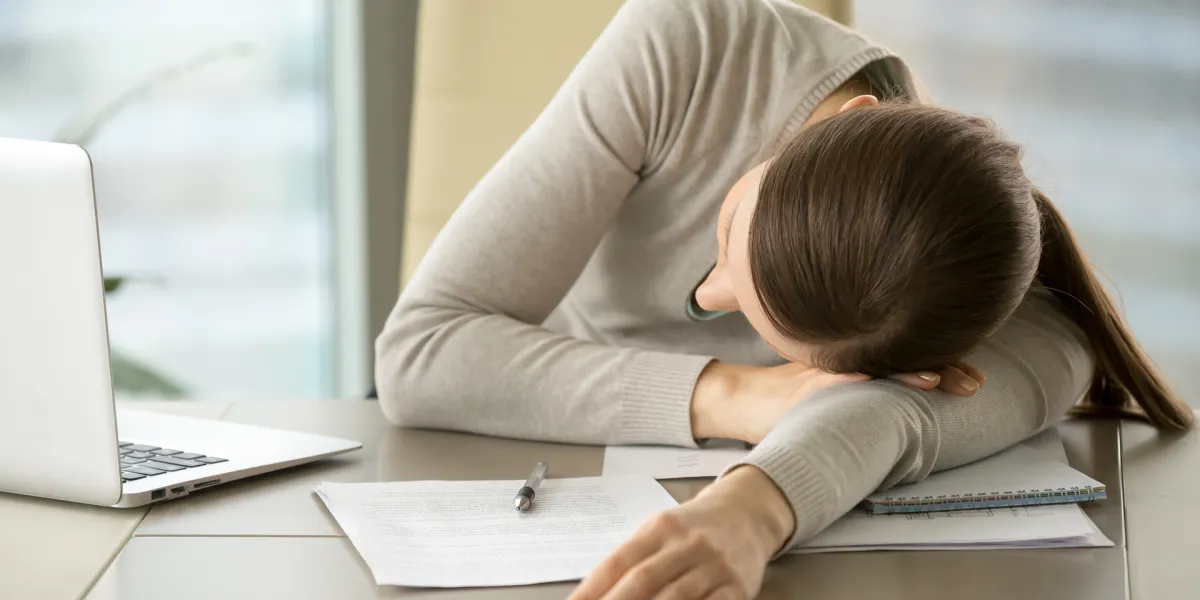 Eine erschöpfte Mitarbeiterin, die ein hohes Arbeitspensum bewältigen muss, leidet unter psychischen Belastungsfaktoren. © Shutterstock, fizkes