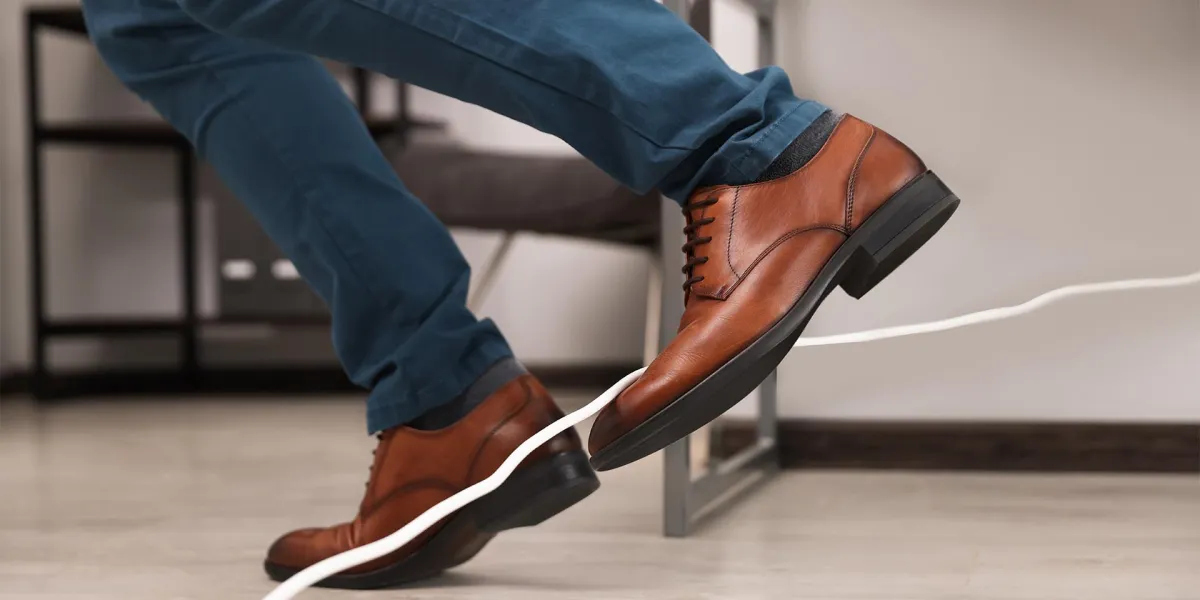 Ein Mitarbeitender stolpert über ein Kabel im Büro. Einige Gefahren im Büro könnt ihr ganz leicht minimieren. © Adobe Stock, New Africa