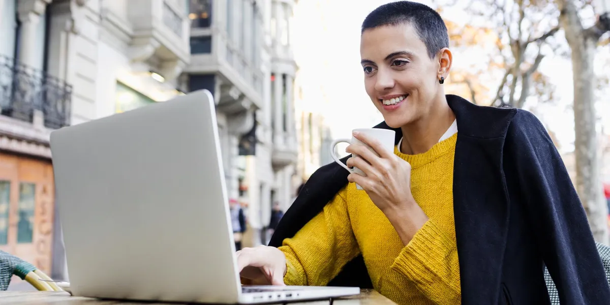 Eine Kleinunternehmerin an einem Laptop mit einem Kaffee in der Hand freut sich über die neuen Änderungen durch das Wachstumschancengesetz. © Adobe Stock, Marcos