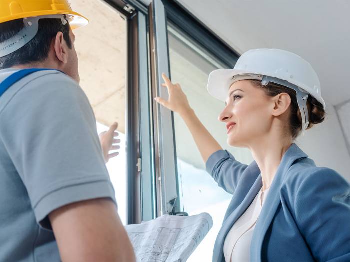 Sicherheitsfachkraft bespricht Arbeitsschritte und Risiken auf einer Baustelle mit einem Mitarbeitenden.