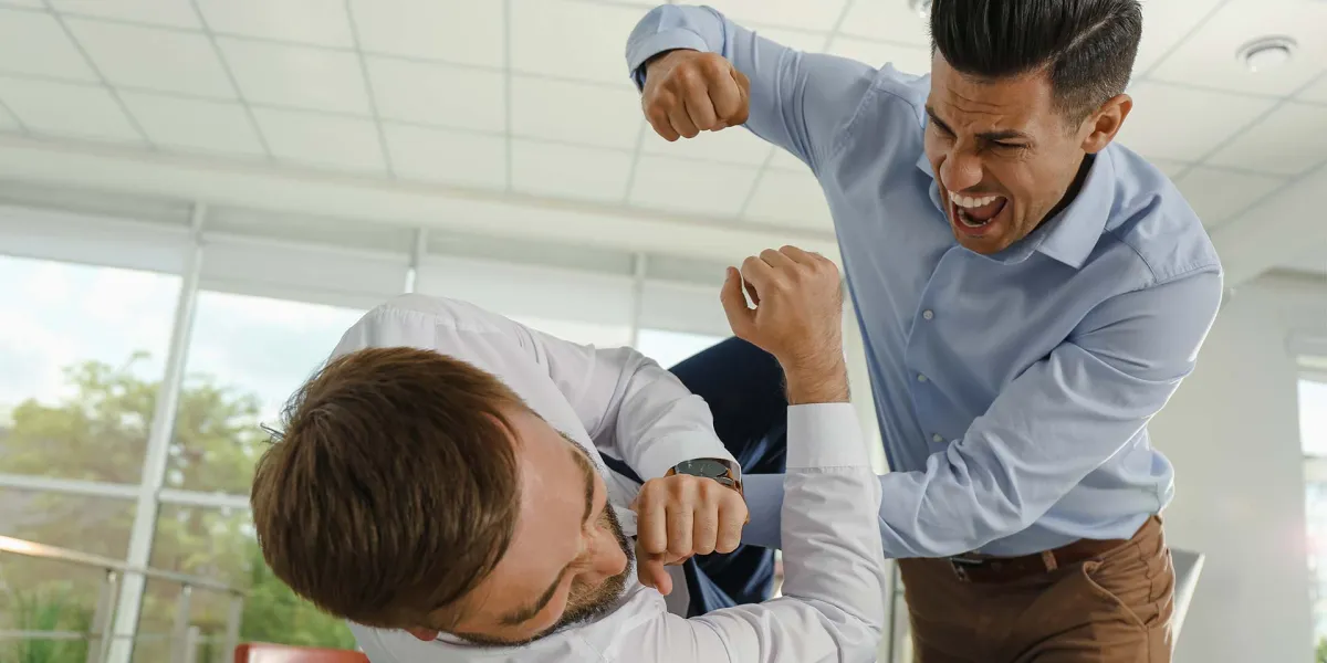 Ein Mitarbeiter übt körperliche Gewalt am Arbeitsplatz an seinem Kollegen aus. © Adobe Stock, New Africa