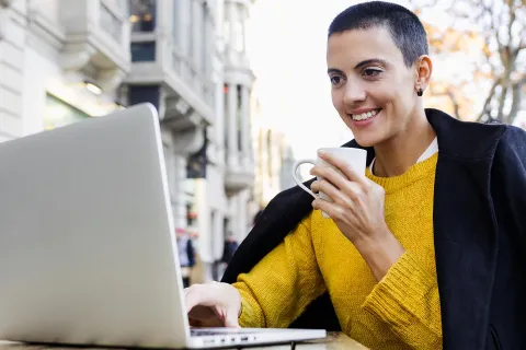 Eine Kleinunternehmerin an einem Laptop mit einem Kaffee in der Hand freut sich über die neuen Änderungen durch das Wachstumschancengesetz. © Adobe Stock, Marcos
