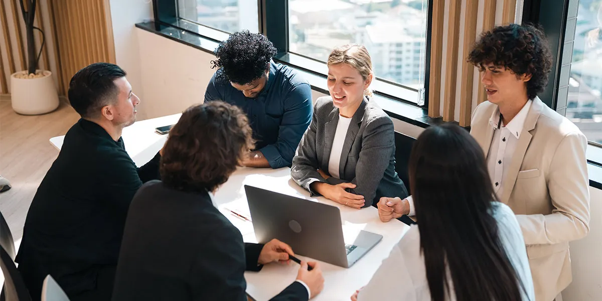 Eine Gruppe von Mitarbeitern sitzen bei einem Meeting und besprechen Vorgehensweisen zur Risikominimierung im Rahmen des Compliance Managements.