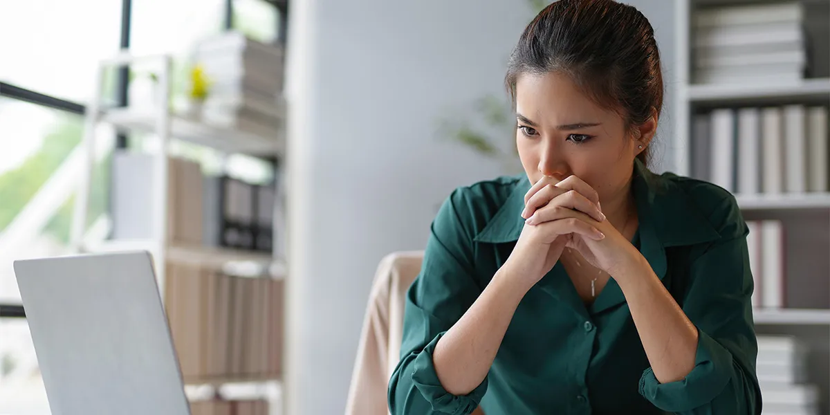 Mitarbeiterin sitzt unter Schock am Arbeitsplatz nach einem Arbeitsunfall im Team.